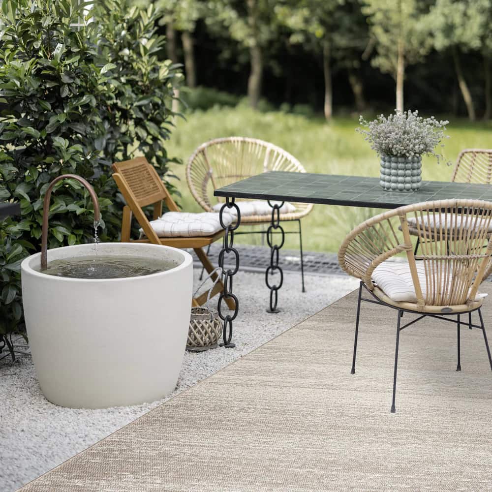 Tapis extérieur beige Edito sur une terrasse en bois aménagée avec un salon de jardin contemporain.